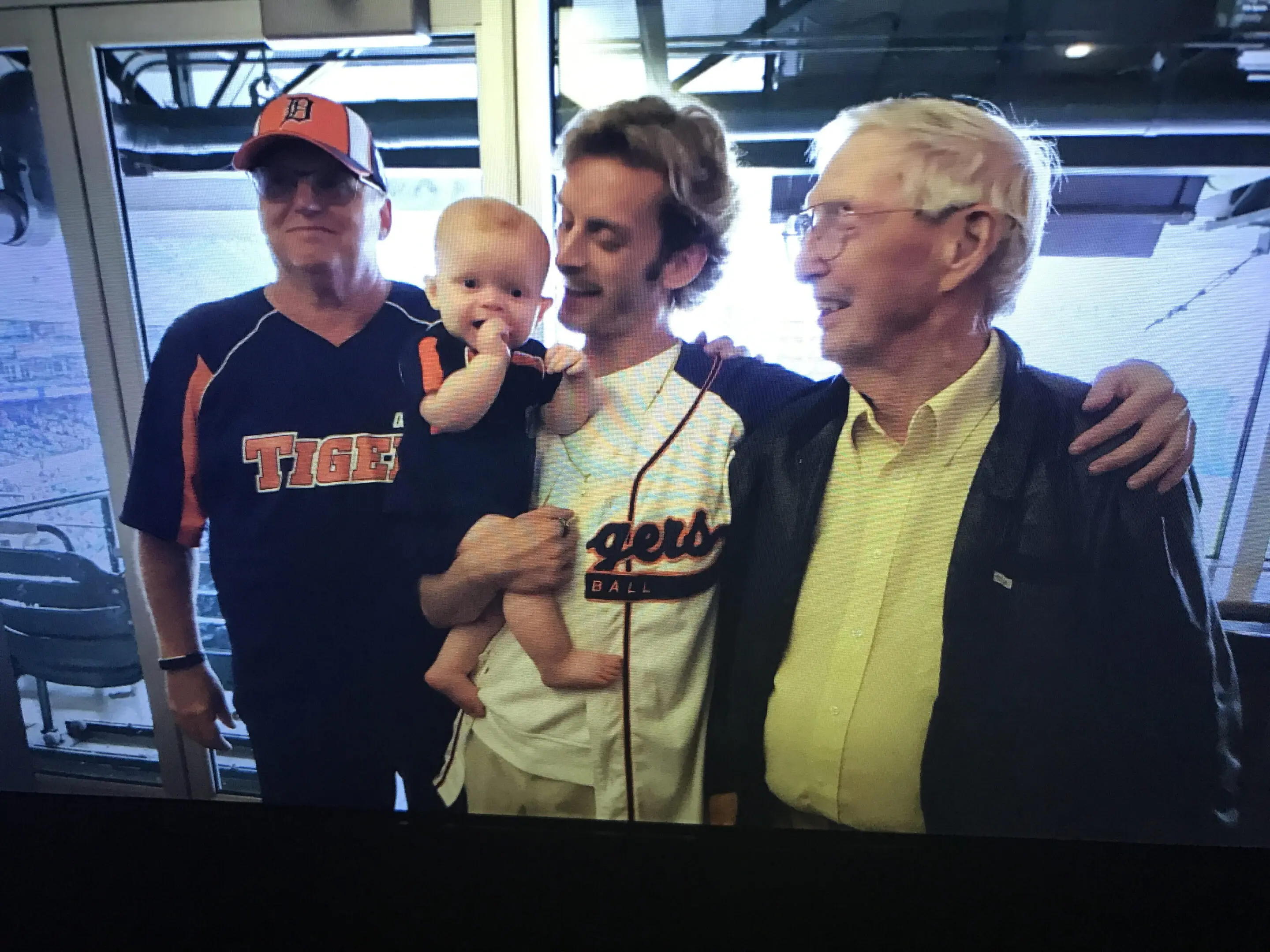 Three men and a baby sharing a joyful moment indoors.