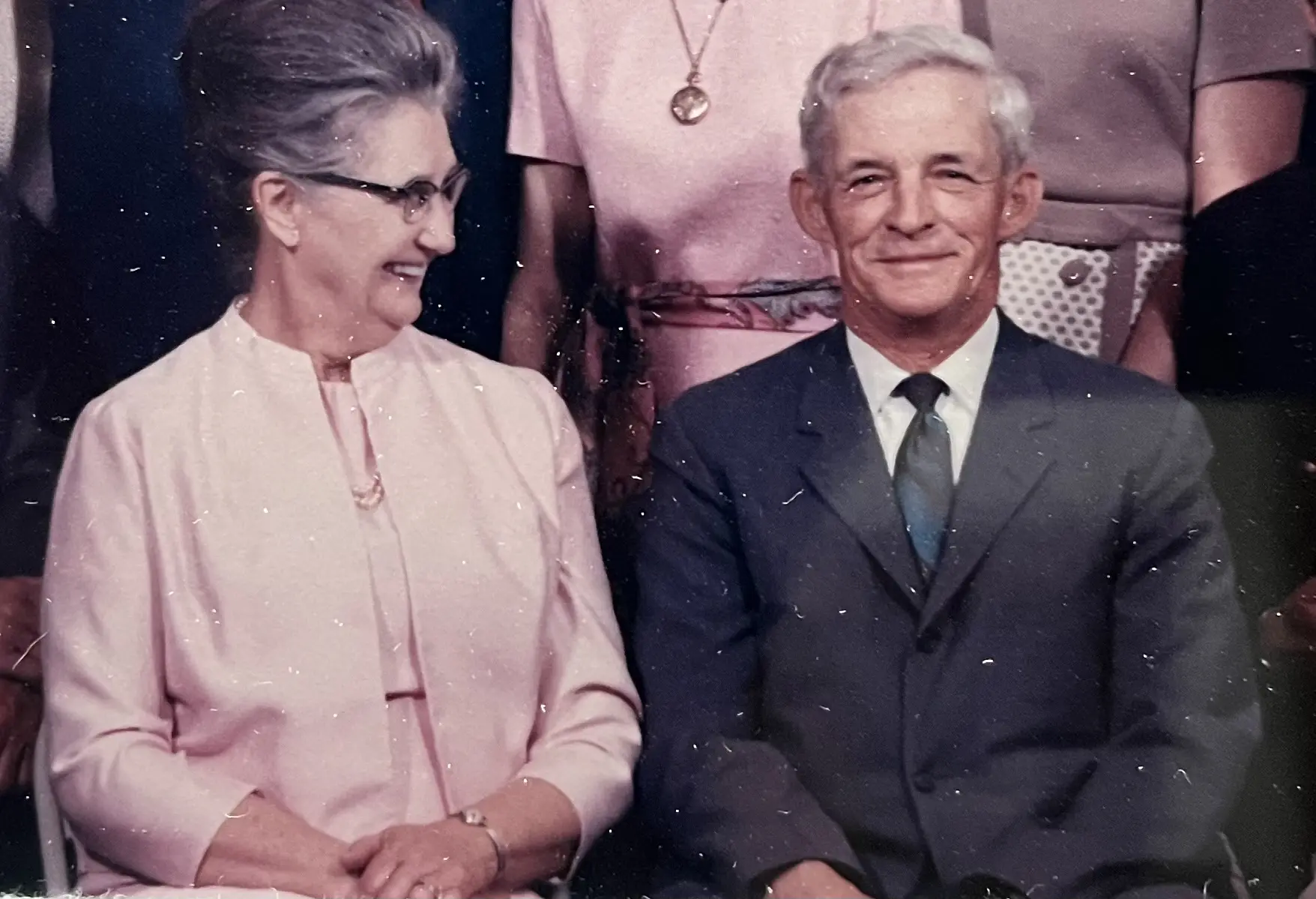 Elderly couple smiling warmly, dressed in formal attire.